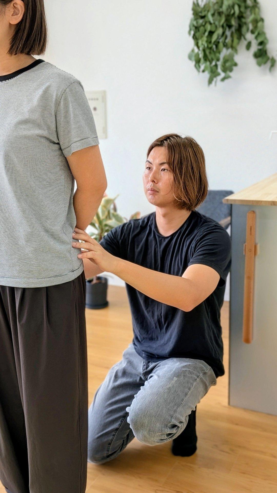 理学療法士が立位で腰部の動きを確認している場面｜Cause Reha FUKUOKA