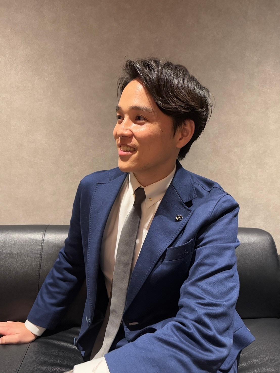 田中雄大が紺色のストライプダブルスーツを着て立っている写真