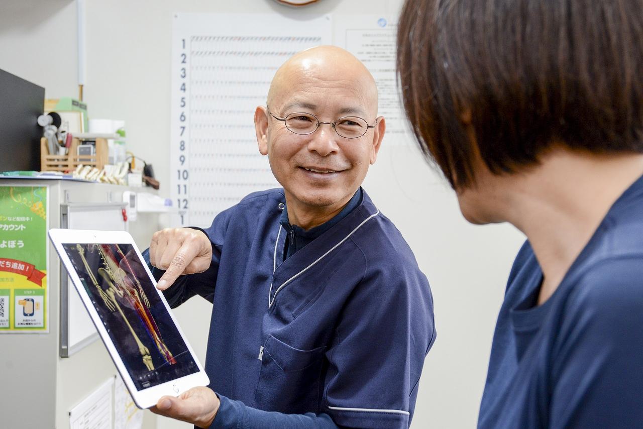 豊岡整体よぼう院長が患者さんにタブレットで説明している