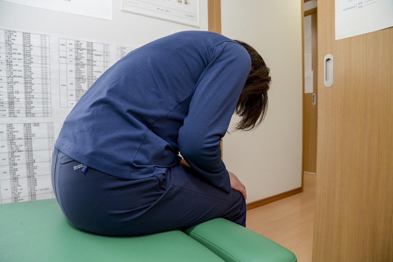 【腰痛の動作痛の検査】座位で前屈し痛みを確認している