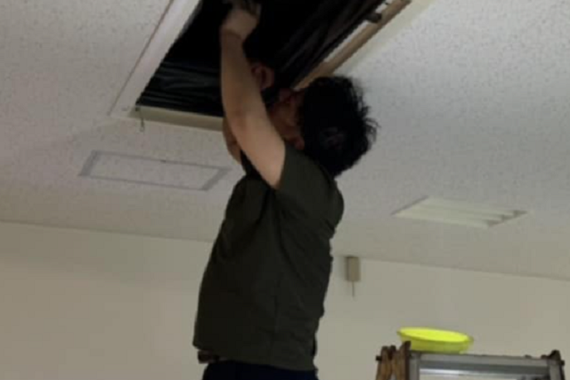 延長ホースでオイルタンクに給油している配達スタッフ