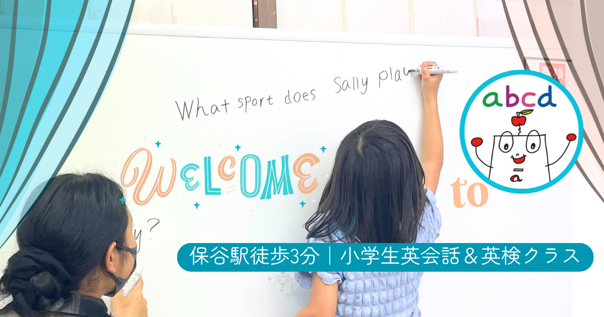 アブクドゥイングリッシュスクール（abcd English School）英文を書く小学生の女の子とサポートするネイティブ講師の様子