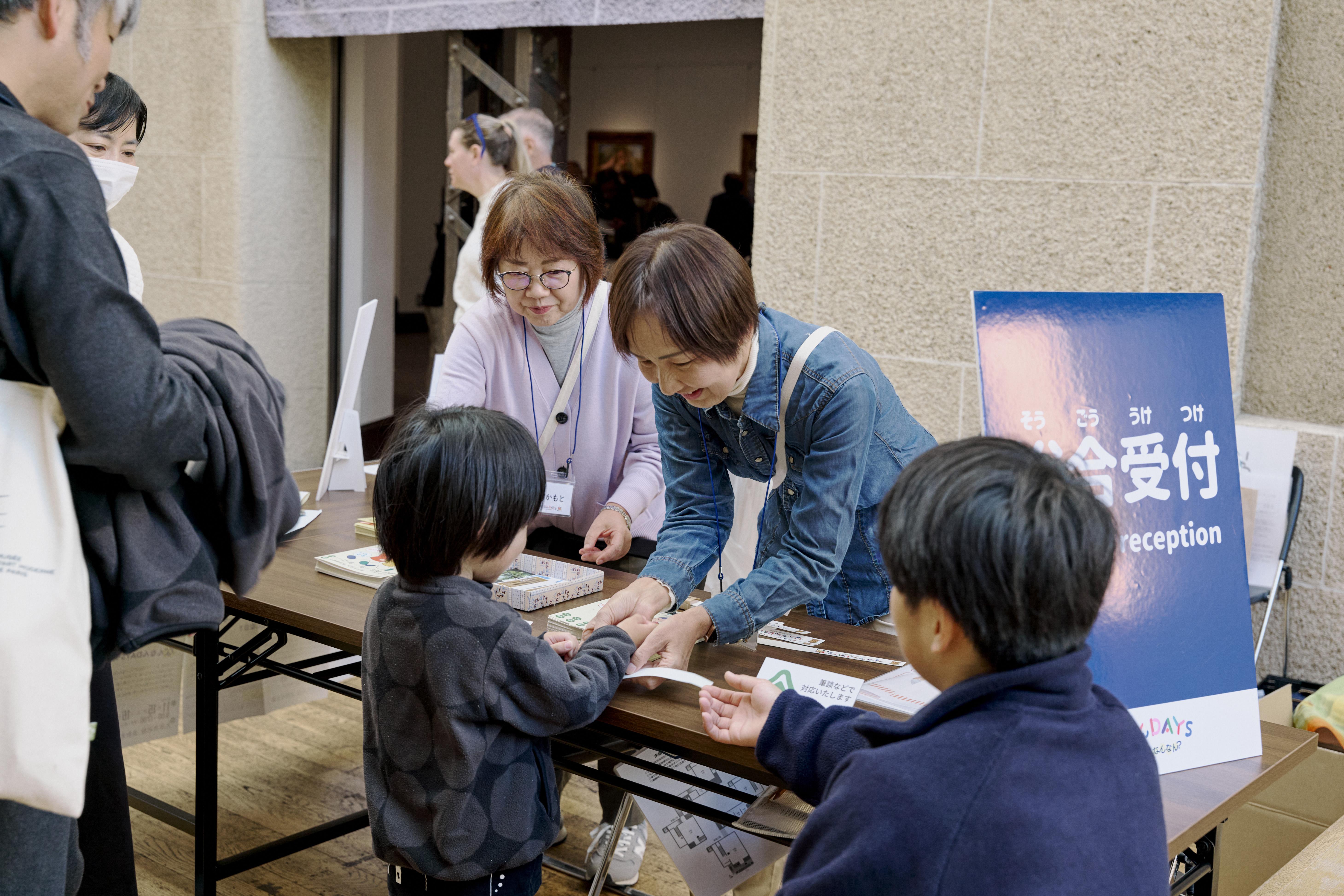 総合受付で参加者に紙リストバンドを巻くスタッフ