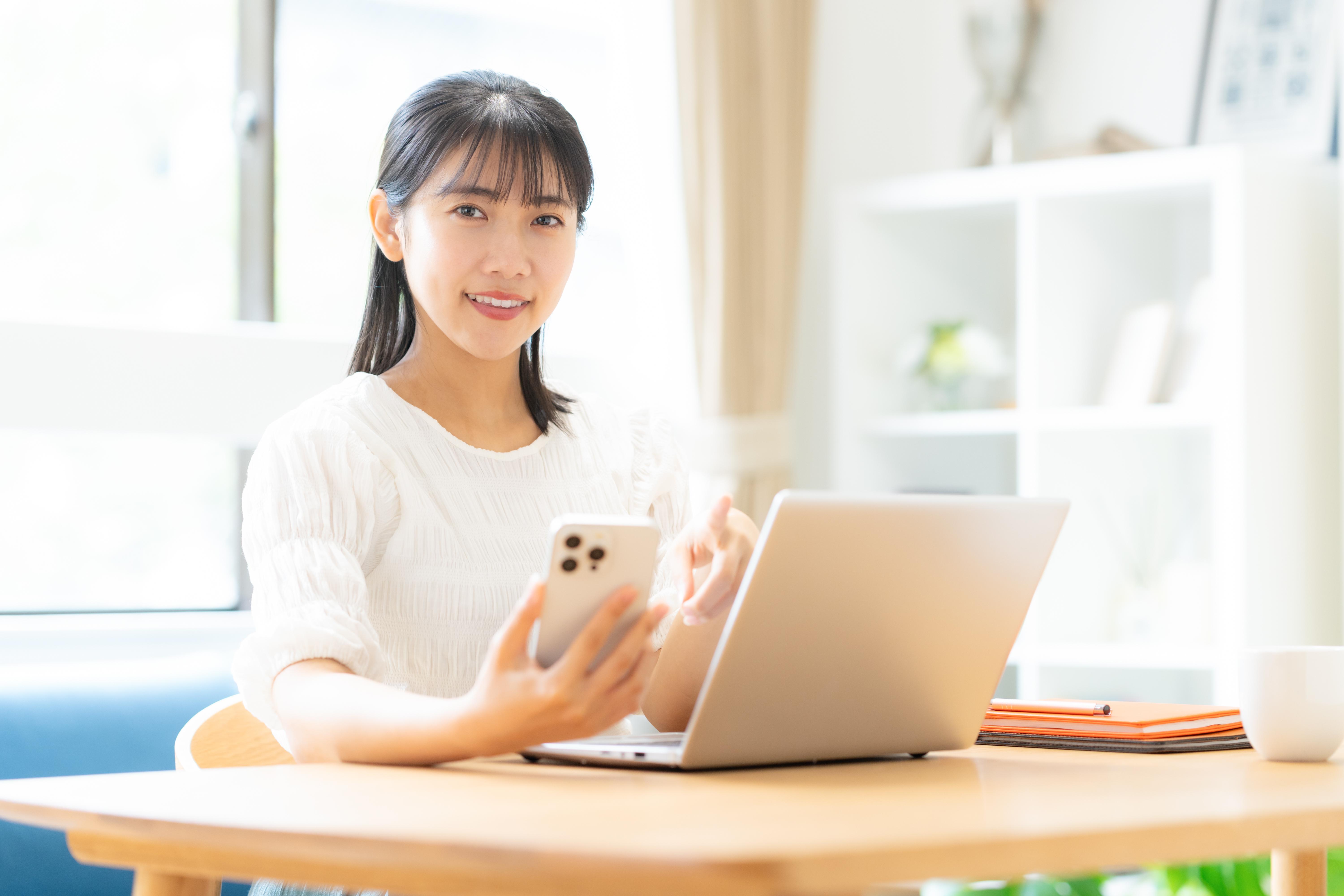 女性がスマホとPCを使っている写真