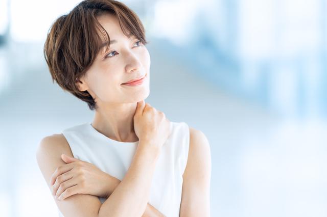 首すじを押さえてほほ笑む女性