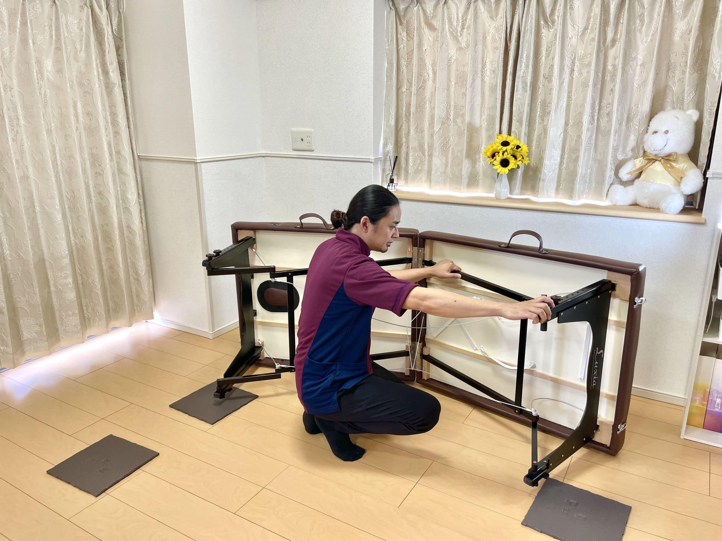出張整体パピル代表の下里が施術ベッドを設置している写真