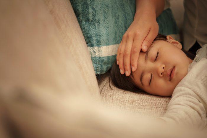 子供の額に手をあてて熱を確認する様子
