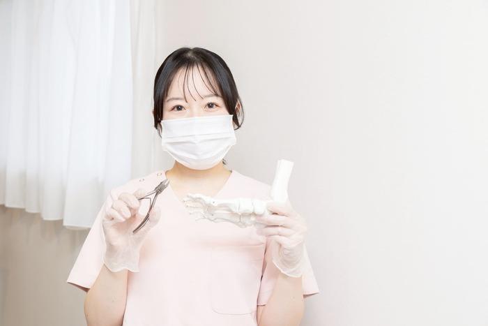 看護師がニッパーと足の模型を持っている