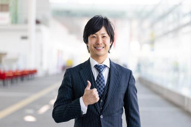 グッドサインをするスーツの男性