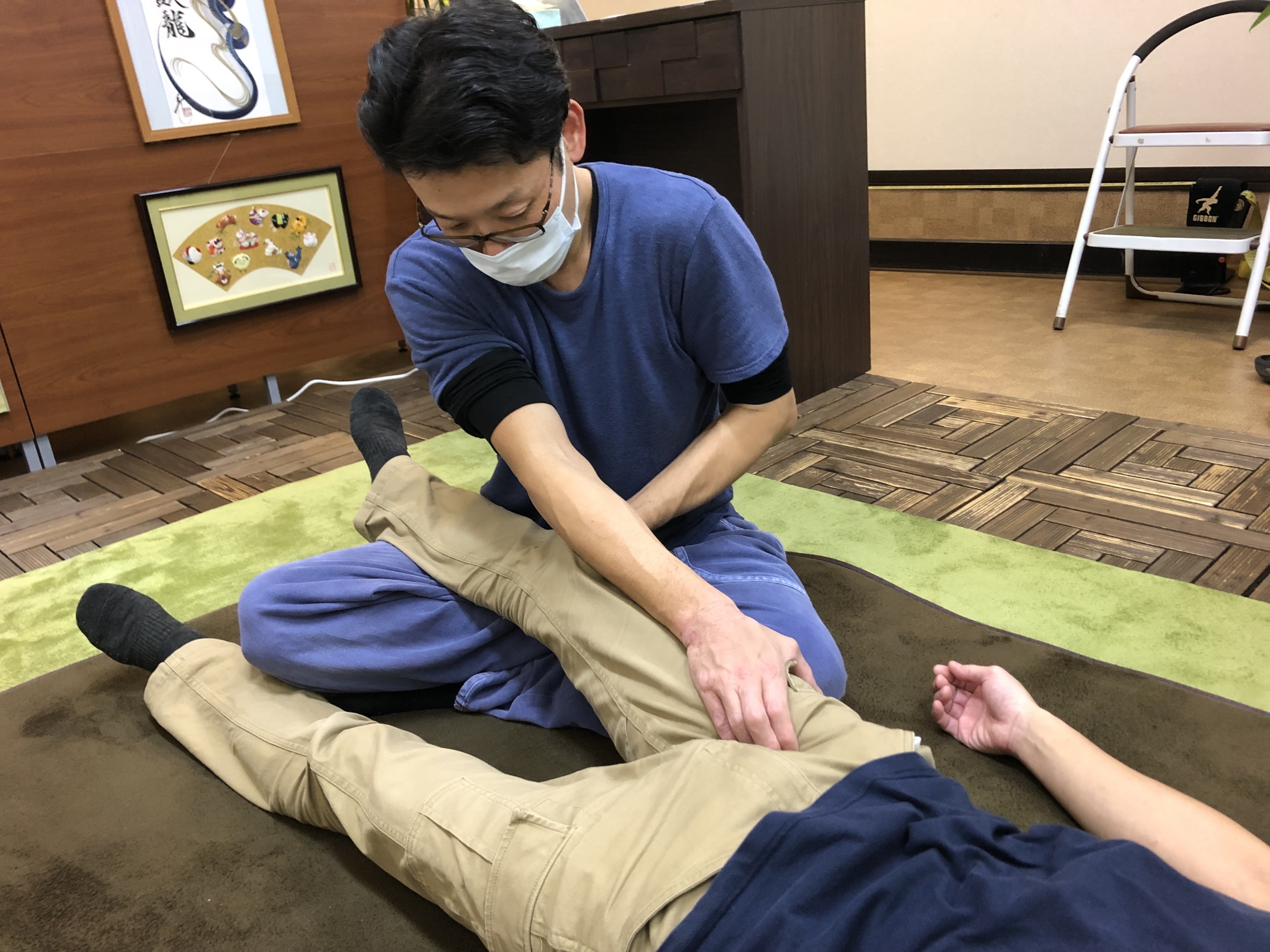 寝ている男性の脚を掴んでいるマスクをつけた男性