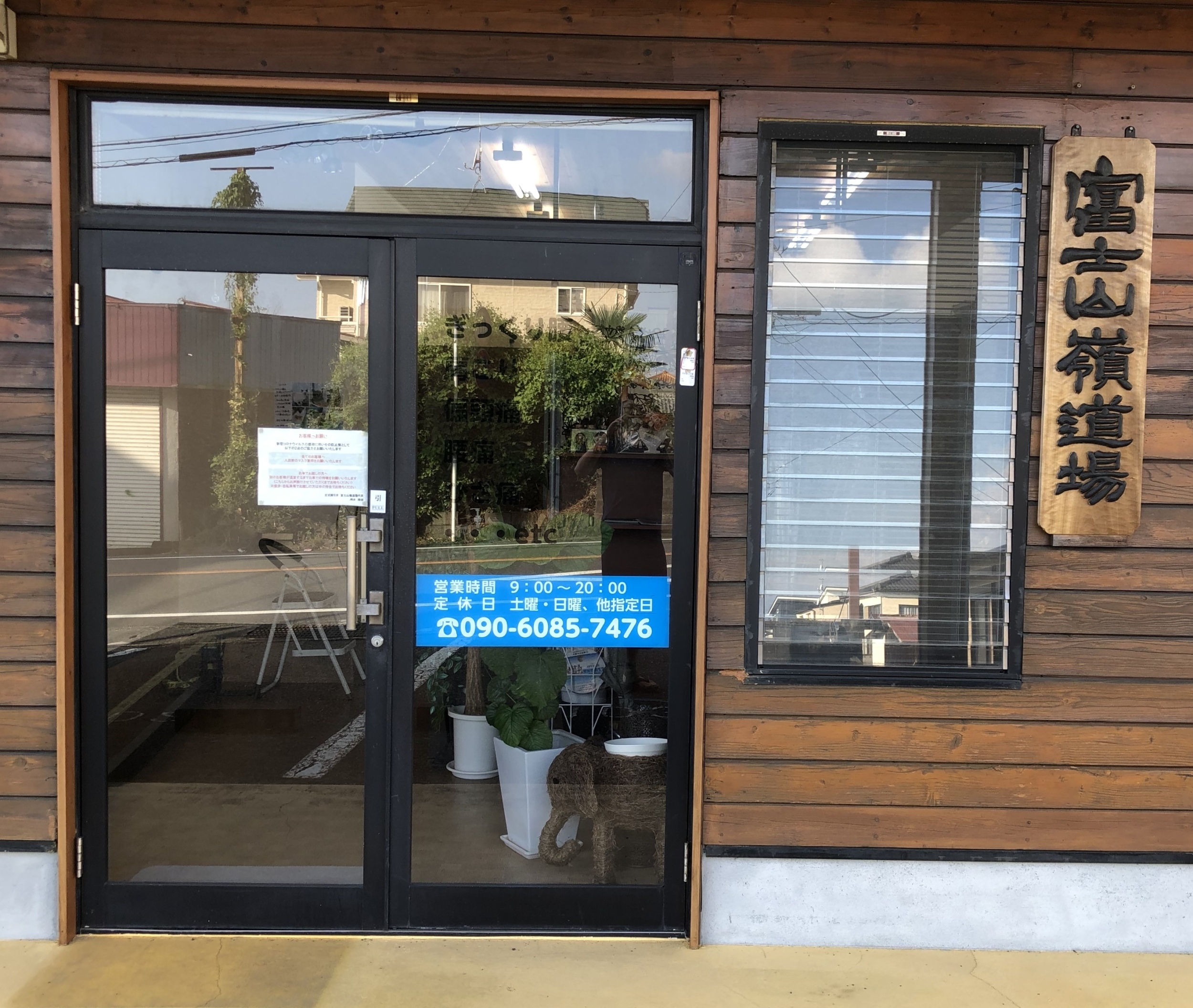 お店の全面ガラスの玄関口と富士山嶺道場の木彫りの看板