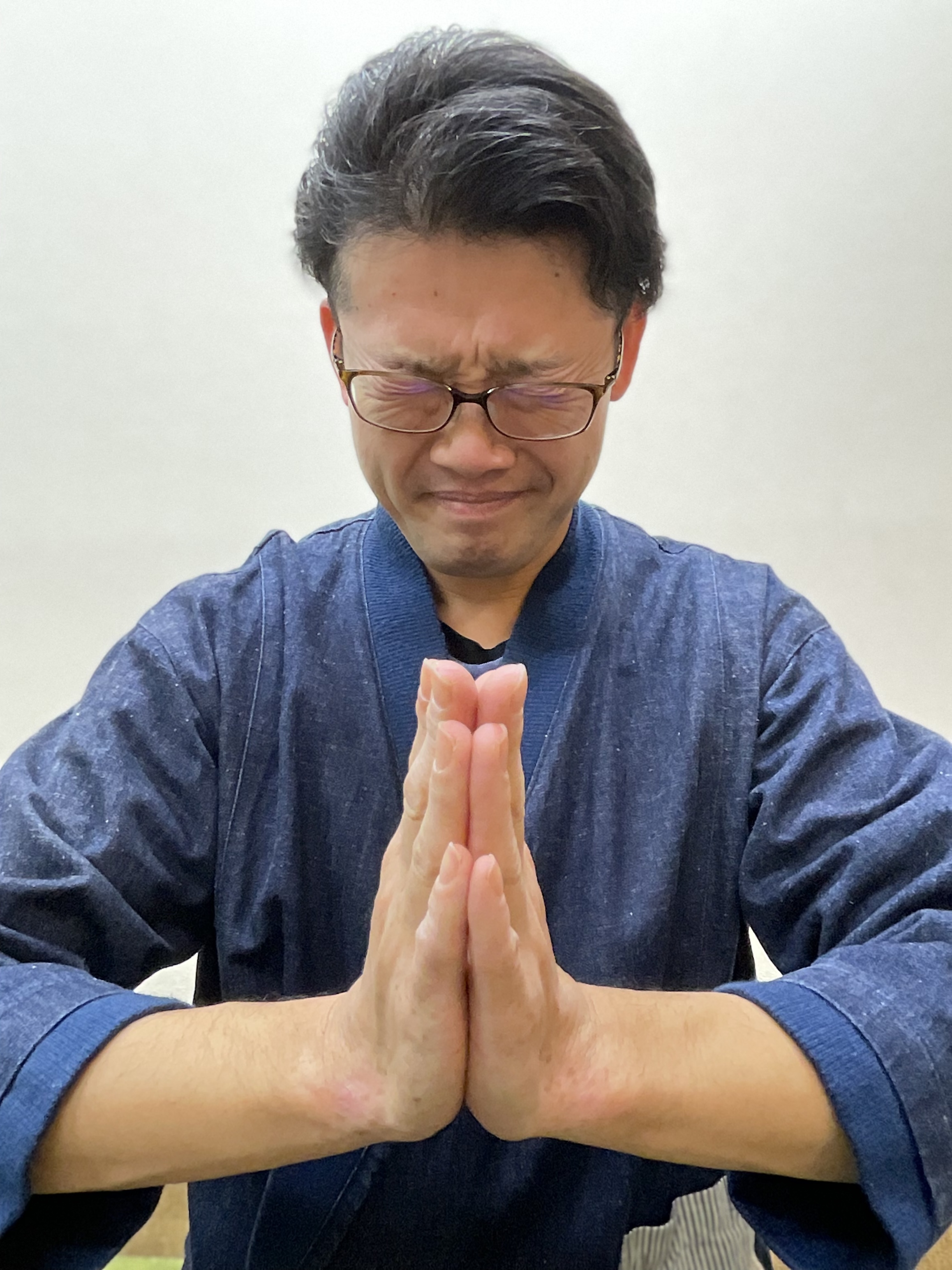 両手を合わせて目をつむる男性