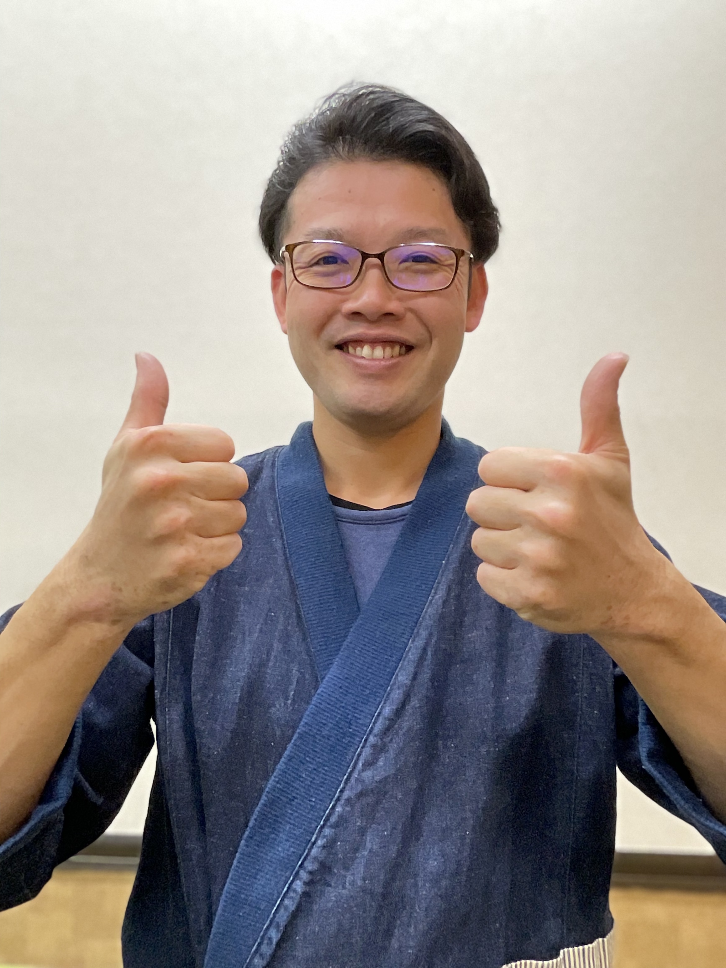 両手の親指を立てていいねポーズをとる笑顔の男性