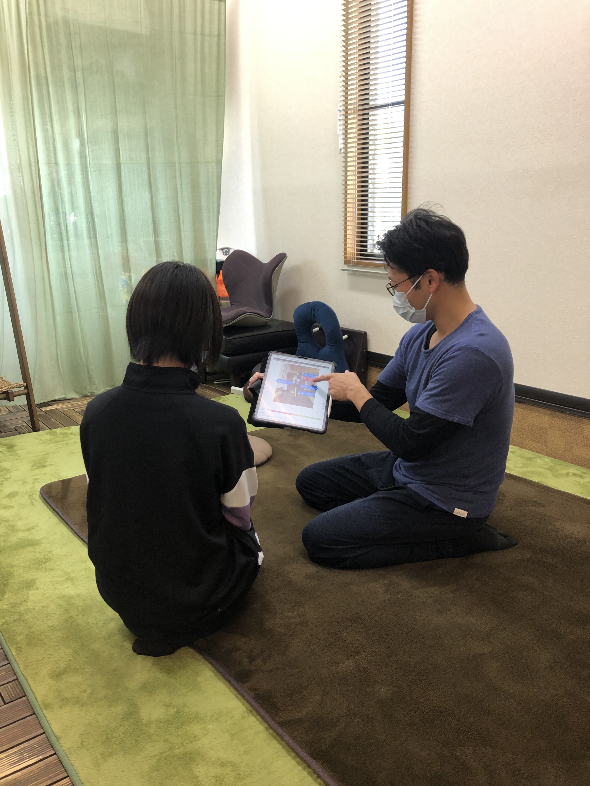 中学生の女子へ タブレットを見せている男性