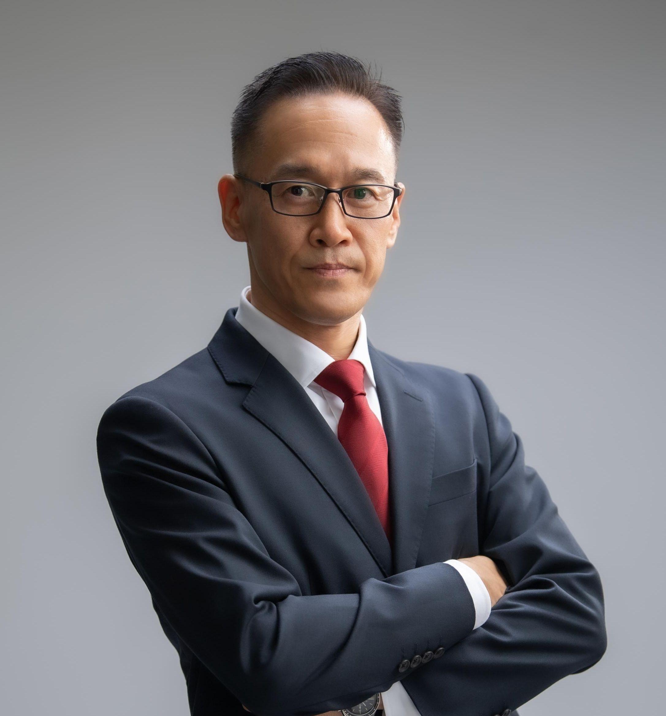 聡明な感じの50歳位の男性、紺色スーツで赤色ネクタイ姿。