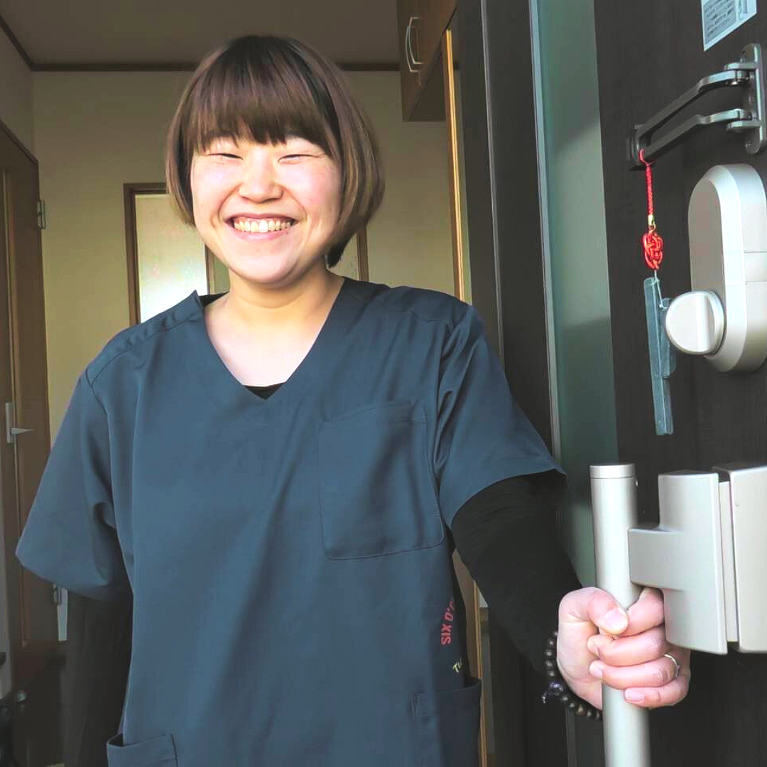 玄関で笑顔で出迎える女性整体師の様子
