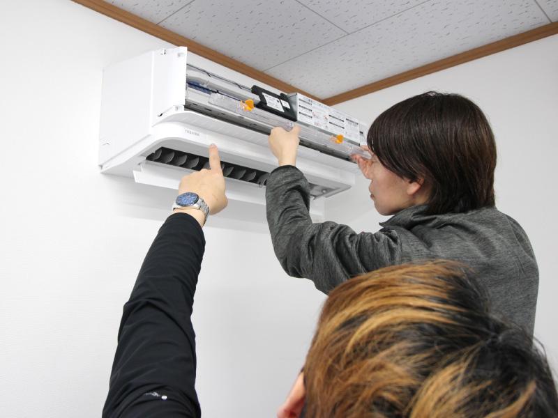 【写真】エアコンクリーニング講習シーン｜お掃除ユニット分解指導の様子