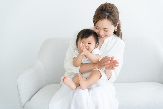 笑顔で赤ちゃんを抱く女性の画像