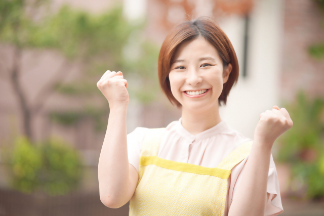笑顔でガッツポーズをする女性職員の画像