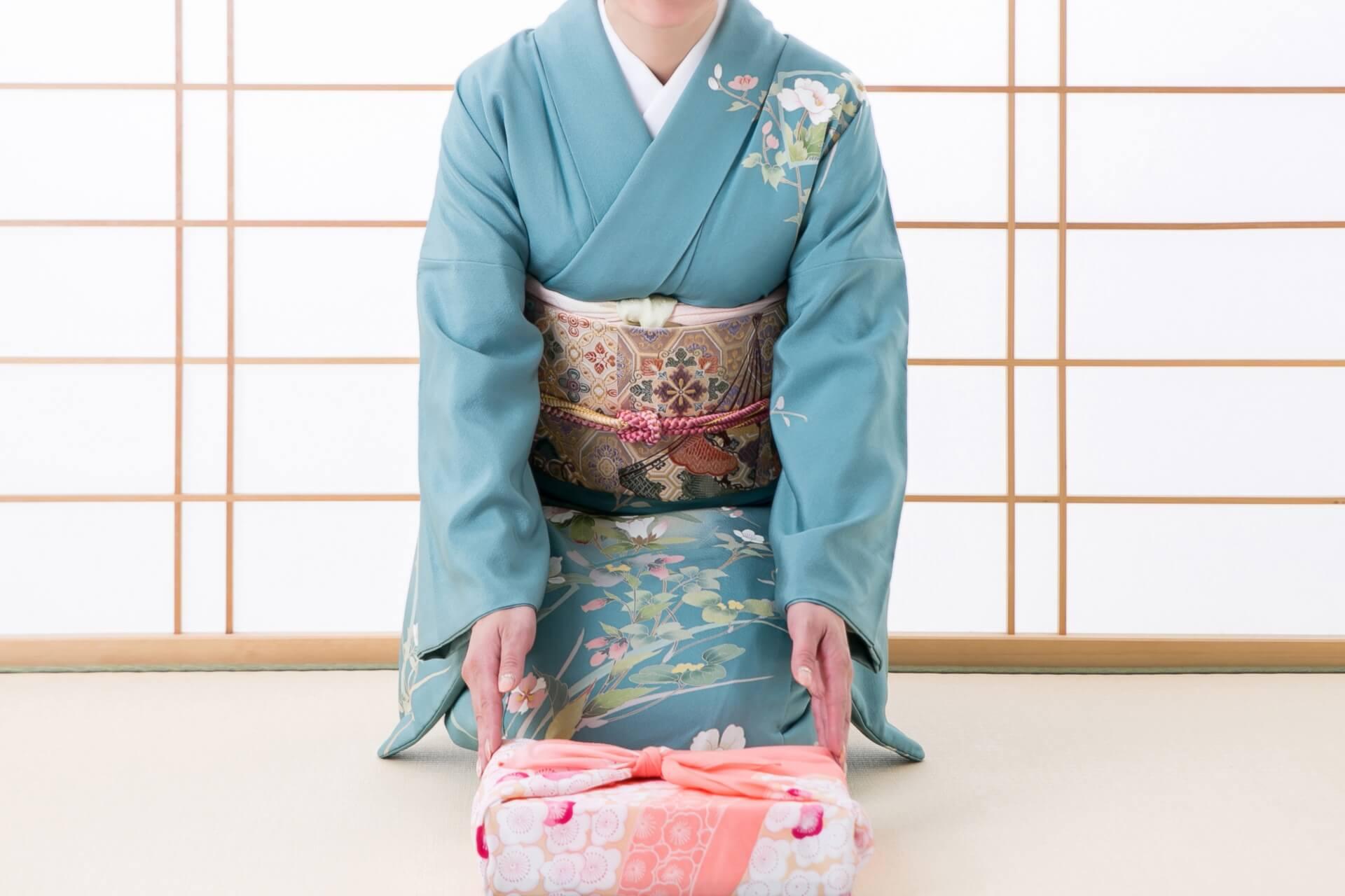 着物を着た女性とお祝いの風呂敷包み