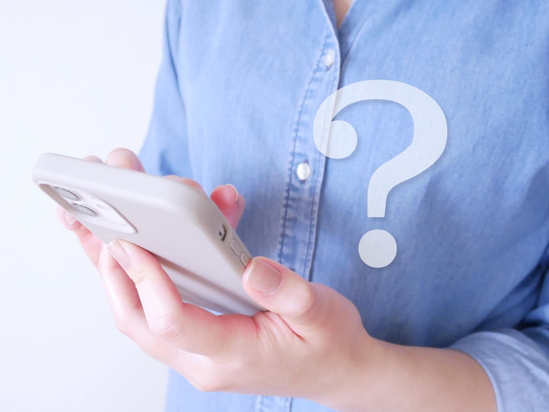 スマホを持つ手とクエスチョンマーク