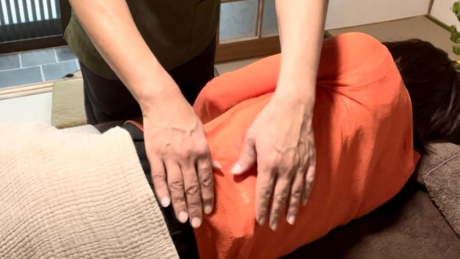 宝塚のそらまめ整体院で提供されている「調息＋コース」の１場面｜横向けのクライアントの腸（側面）と横隔膜にポイントレイキを実施しているところ。