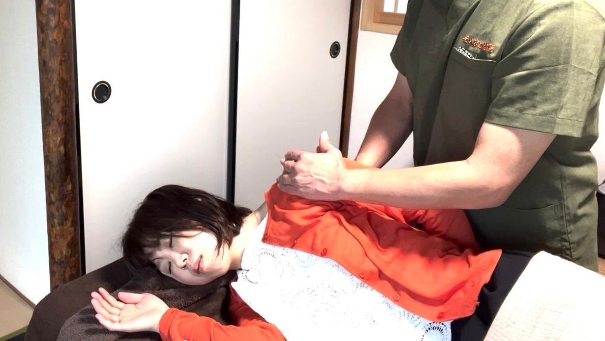 宝塚のそらまめ整体院で提供されている「調息＋コース」の１場面｜横向きに寝ているクライアントの背骨から首の後ろを施術者が優しく整えているところ。