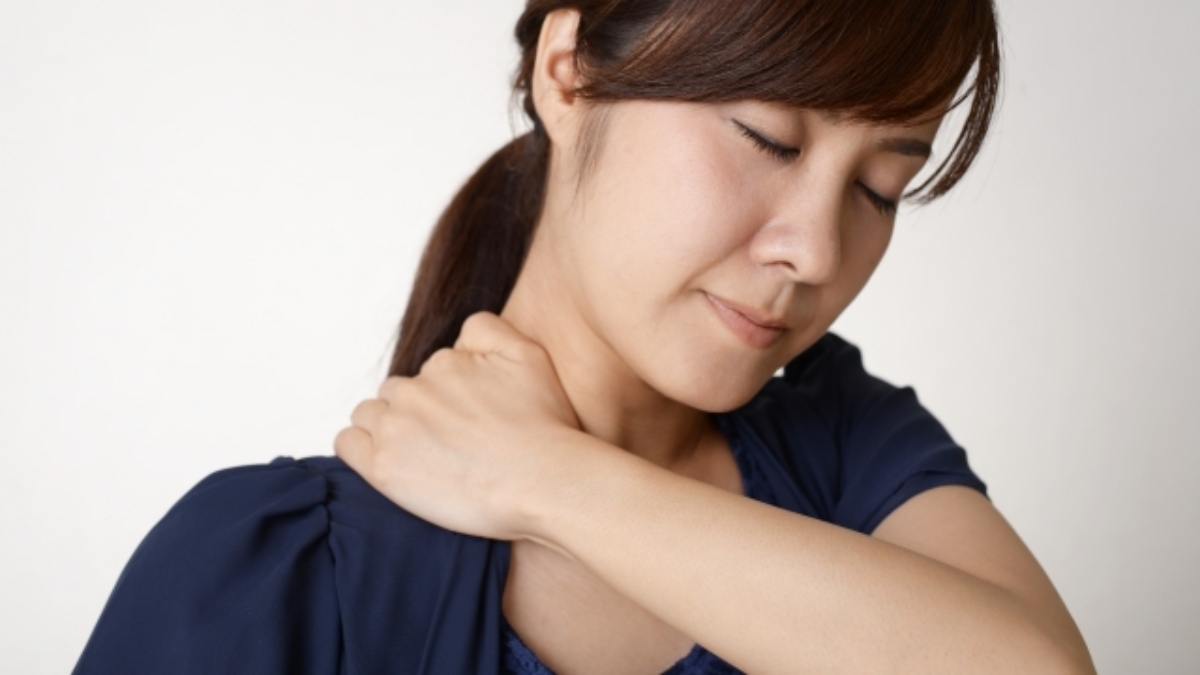 背中や肩の違和感に悩む女性の様子