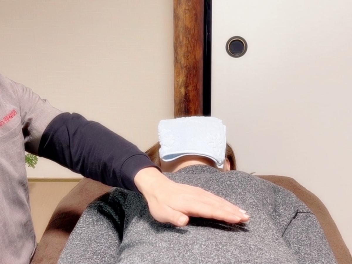 天恵コースの施術例｜胃腸の不調の女性の腹部に手をかざしてレイキ療法を行っているところ