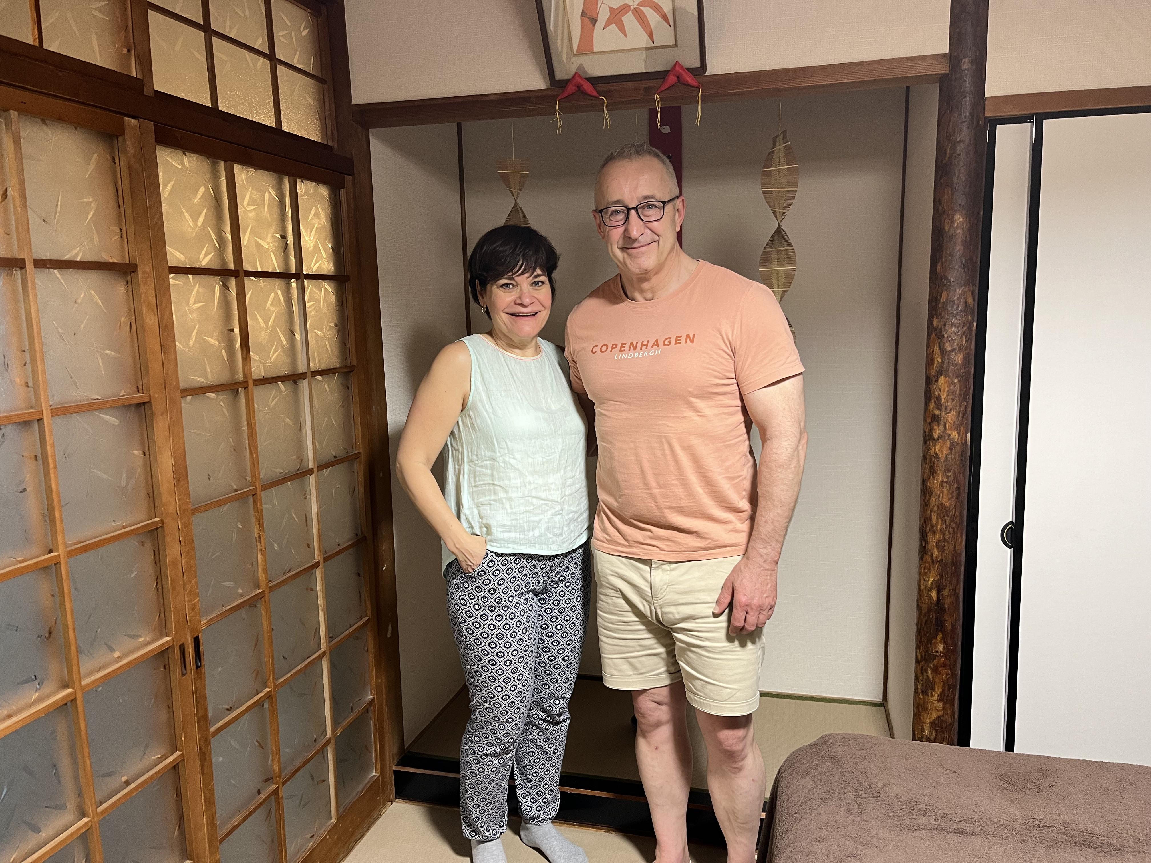 A commemorative photo of a German couple standing in a Japanese tatami room after their Usui Reiki session at Soramame Seitai Clinic.