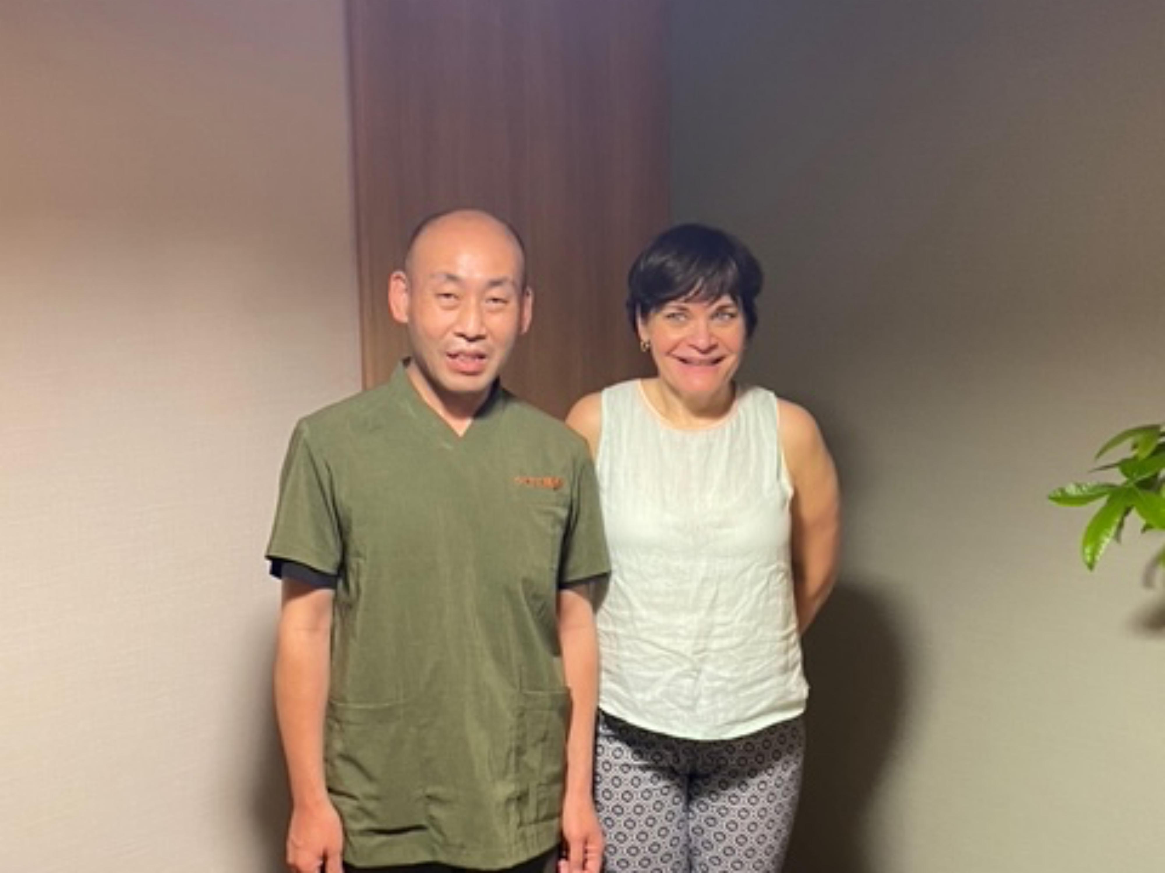 A German guest and practitioner Mizuno standing together in a Japanese-style treatment room after a Reiki session.