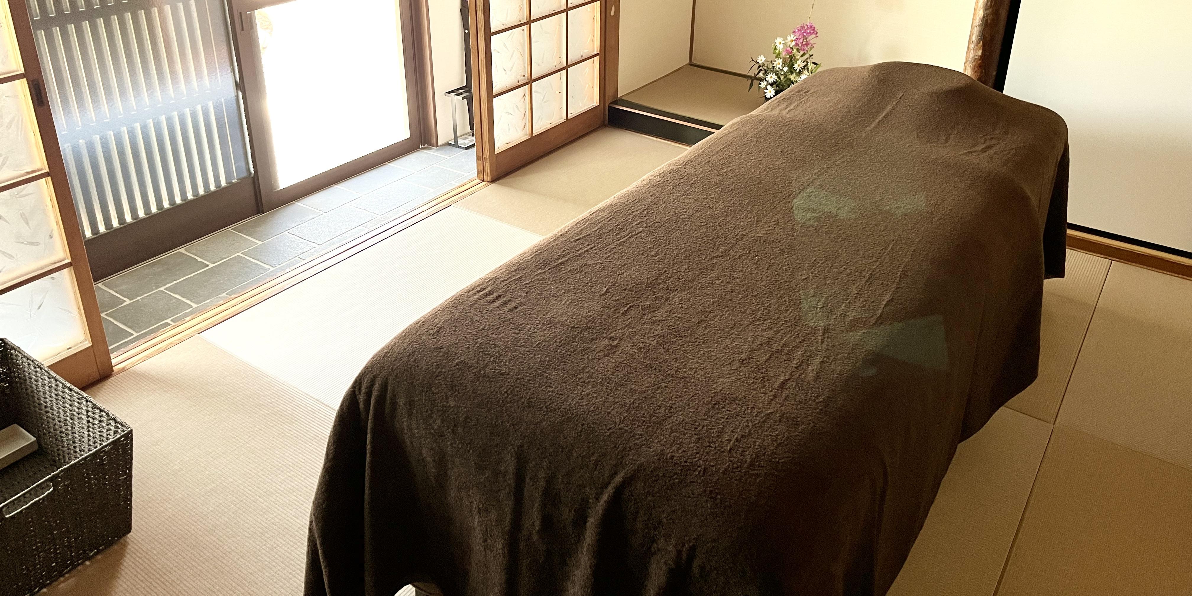 A traditional Japanese tatami room prepared with a professional massage bed for guests who prefer bed-style Reiki sessions.