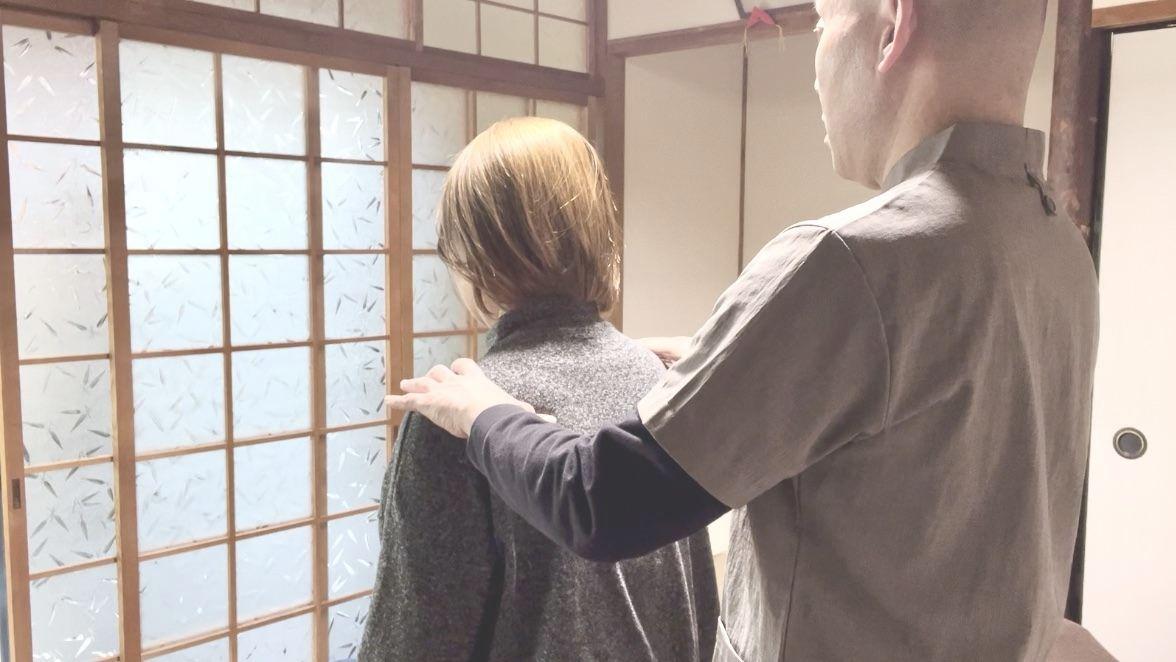 和室の落ち着いた空間で、女性の肩に優しく手を当てる臼井式レイキの施術風景。安心感を醸成し、副交感神経を優位にするためのアプローチ。