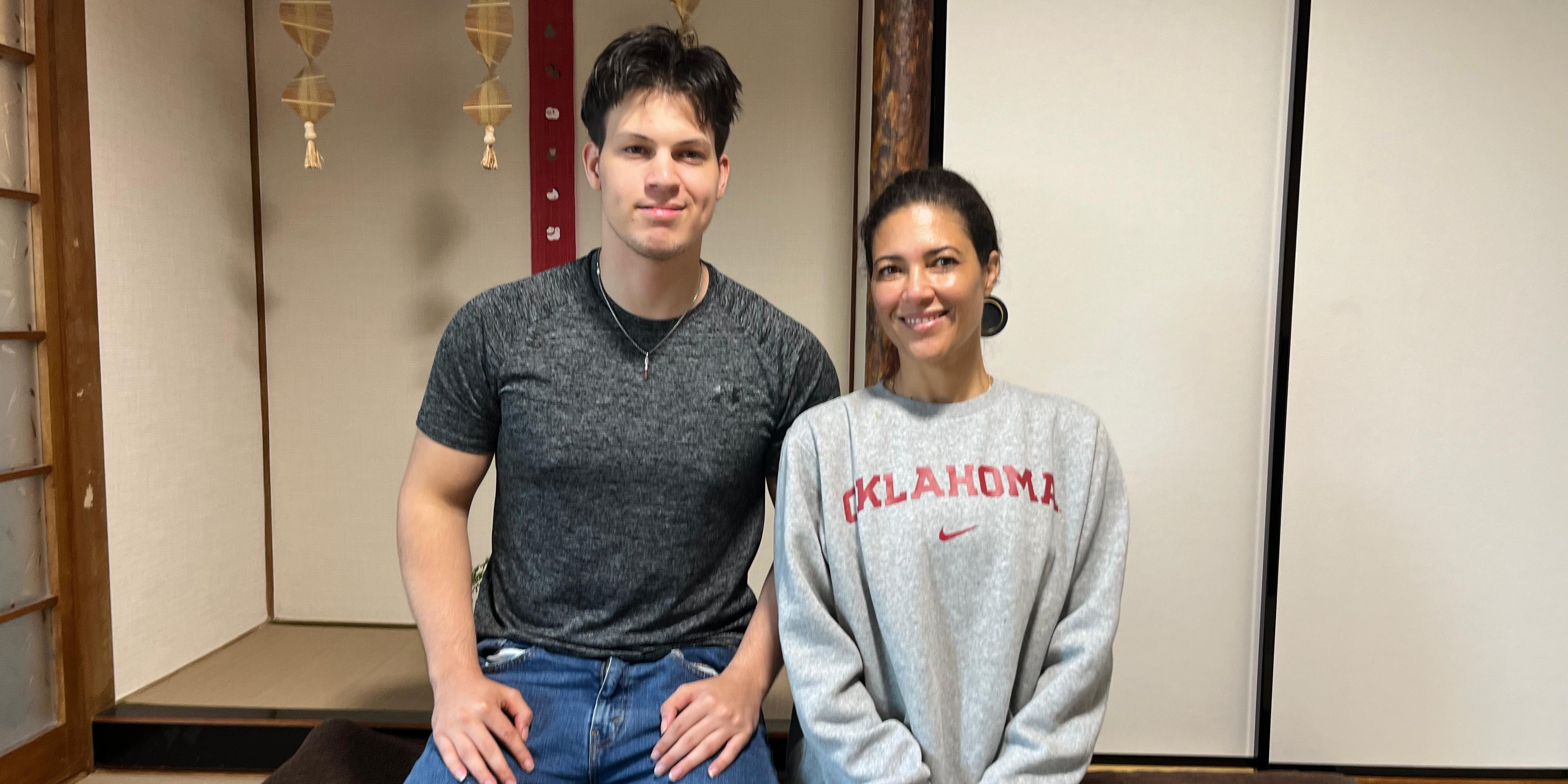 A commemorative photo of a couple from United Kingdom, smiling and sitting on a futon in a traditional Japanese tatami room after their Reiki session.