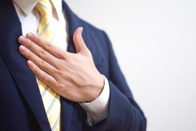 胸に手を当てるスーツの男性