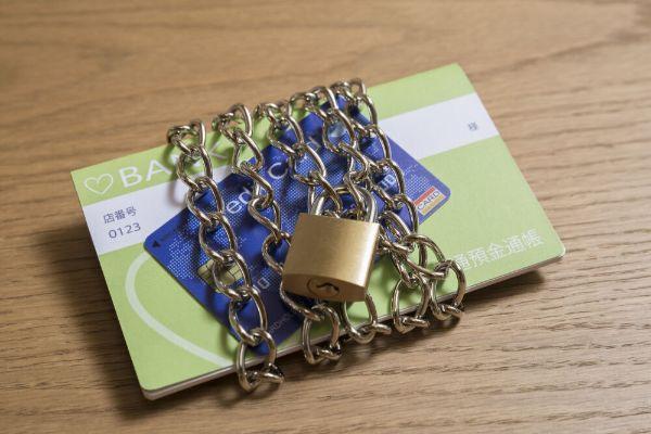 鎖と南京錠でロックされた通帳の写真。口座凍結や資産凍結を表現するもの