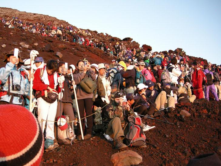 富士山山頂で朝日に向かって写真を撮る