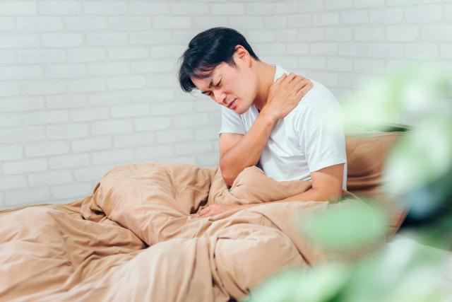 寝違えで首を痛がる男性