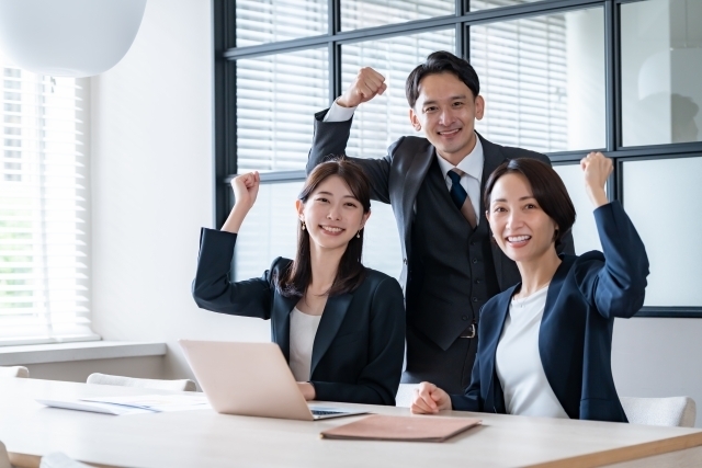 ガッツポーズするスタッフ。成功をイメージする写真