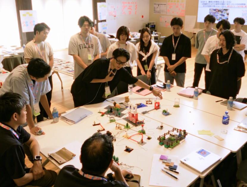 ブロックで表した関係図を指さしながら、周りの参加者と場を共につくるファシリテーター